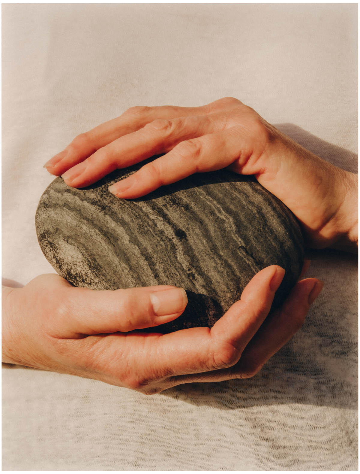 Hands holding a banded beach stone